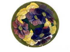 Moorcroft Pottery plate decorated with anemone on green ground, 26cm diameter.
