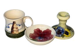 Three pieces of Moorcroft Pottery, Hibiscus bowl, candlestick and mug.