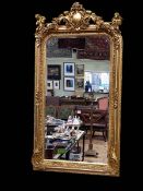 Rectangular gilt framed bevelled wall mirror with cherub and foliate crest, 158cm by 84cm.