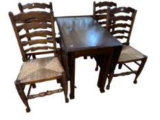 Oak gate leg dining table and set of four rush seated ladder back dining chairs.