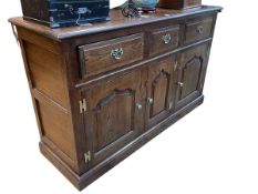 Oak dresser having three drawers above three arched fielded panel cupboard doors,
