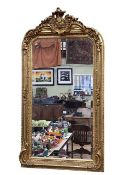 Rectangular gilt framed bevelled wall mirror with foliate decorated crest, 155cm by 84cm.