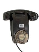 Vintage black wall telephone with rotary dial.