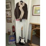 Electric guitar marked Stratocaster Fender and a Vali XL leather jacket.