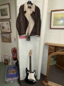 Electric guitar marked Stratocaster Fender and a Vali XL leather jacket.
