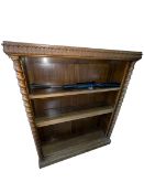 Carved oak open bookcase having three adjustable shelves flanked by twist pillars,