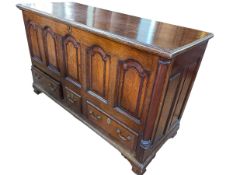 Antique oak and mahogany crossbanded arched fielded panel front mule chest with three base drawers,