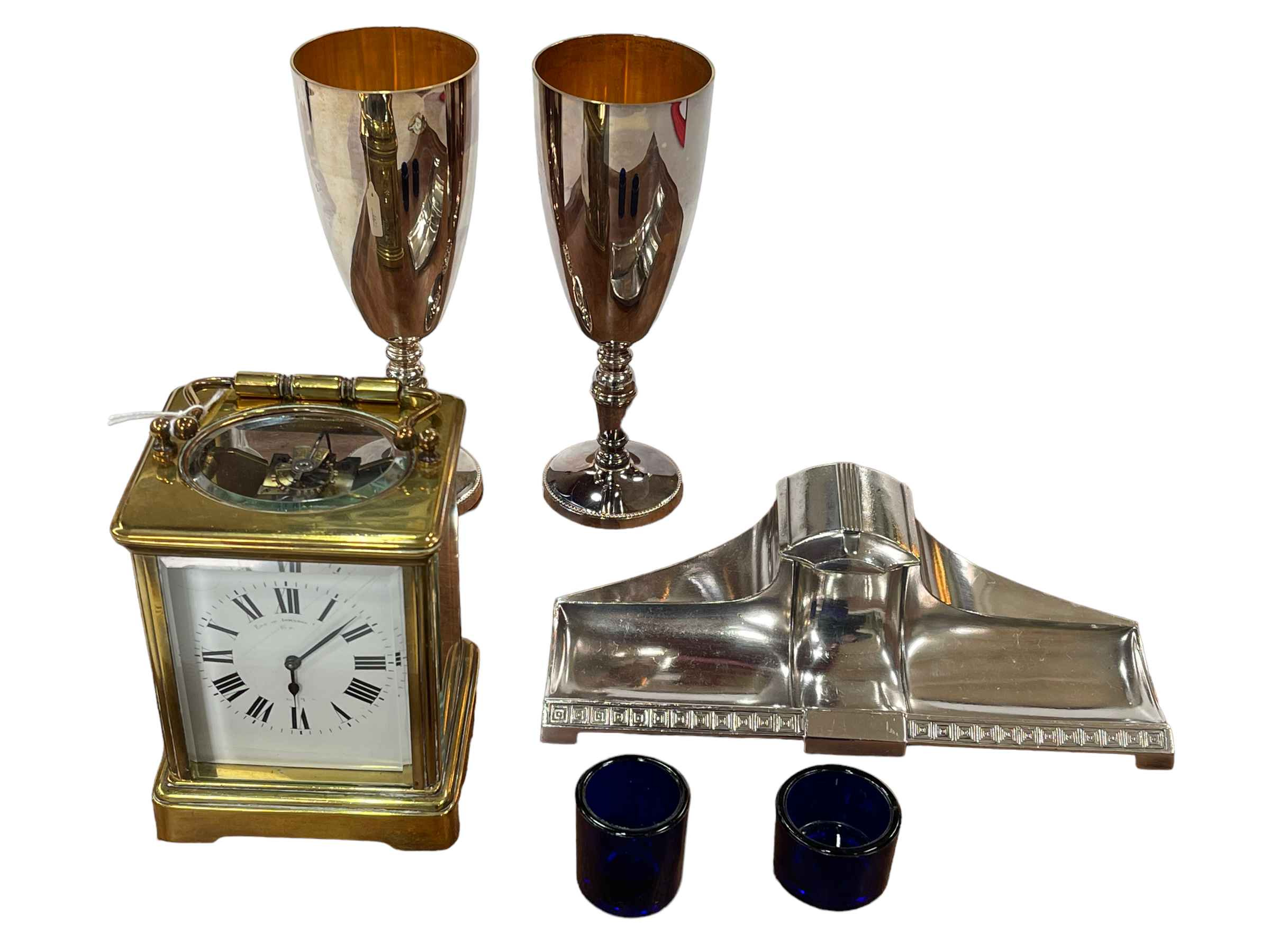 French gilt brass carriage clock, Arts & Crafts inkstand, pair goblets and two blue glass liners.