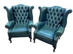 Pair bottle green deep buttoned back and studded leather wing armchairs.