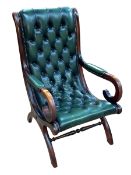 Bottle green deep buttoned and studded leather scroll armchair.