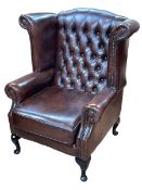 Thomas Lloyd brown deep buttoned back and studded leather wing armchair.