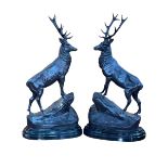 Pair of impressive bronze models of stags in rocky outcrops on marble bases, 74cm high.