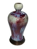 Chinese Sang de Boeuf porcelain vase with flambé and blue glaze and garlic bulb neck on wooden