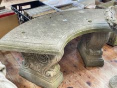 Weathered concave garden bench on scroll decorated pillars, 42cm by 106cm by 38cm.