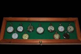 Collection of eleven pocket watches in glass display case.