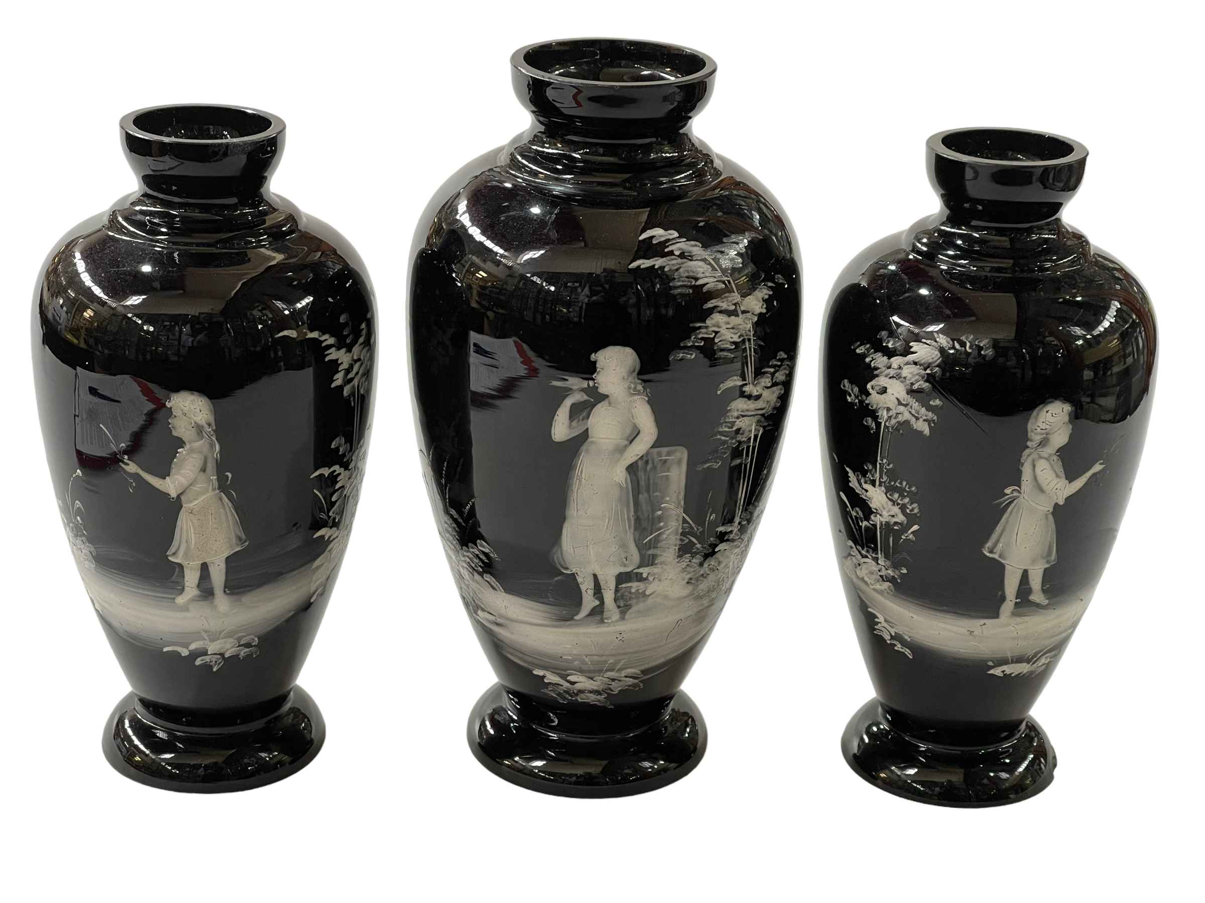 Set of three black glass Mary Gregory garniture of vases, largest 23cm.