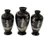 Set of three black glass Mary Gregory garniture of vases, largest 23cm.