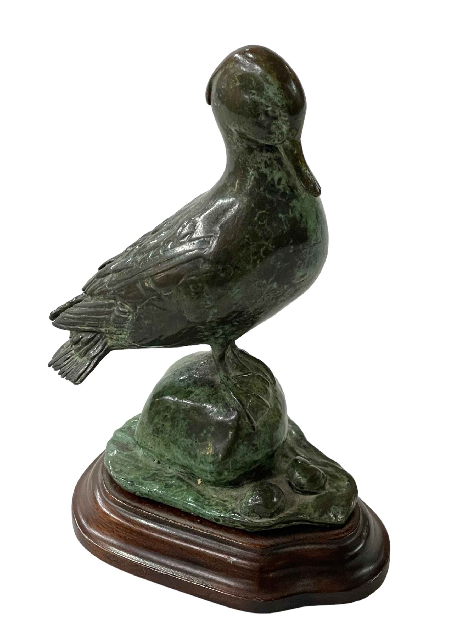 Green patinated bronze model of a duck on wooden stand, 13cm high.