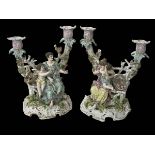 Pair Continental porcelain candelabra featuring maidens and cherubs on garden bench with birds and