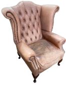 Dusky pink button backed and studded wing armchair.
