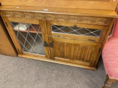 Oak leaded glazed two door bookcase and oak linen fold panel entertainment cabinet.