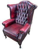 Ox blood buttoned and studded leather wing back armchair.