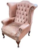 Dusky pink button backed and studded wing armchair.