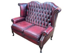 Ox blood buttoned and studded leather two seater wing back settee.