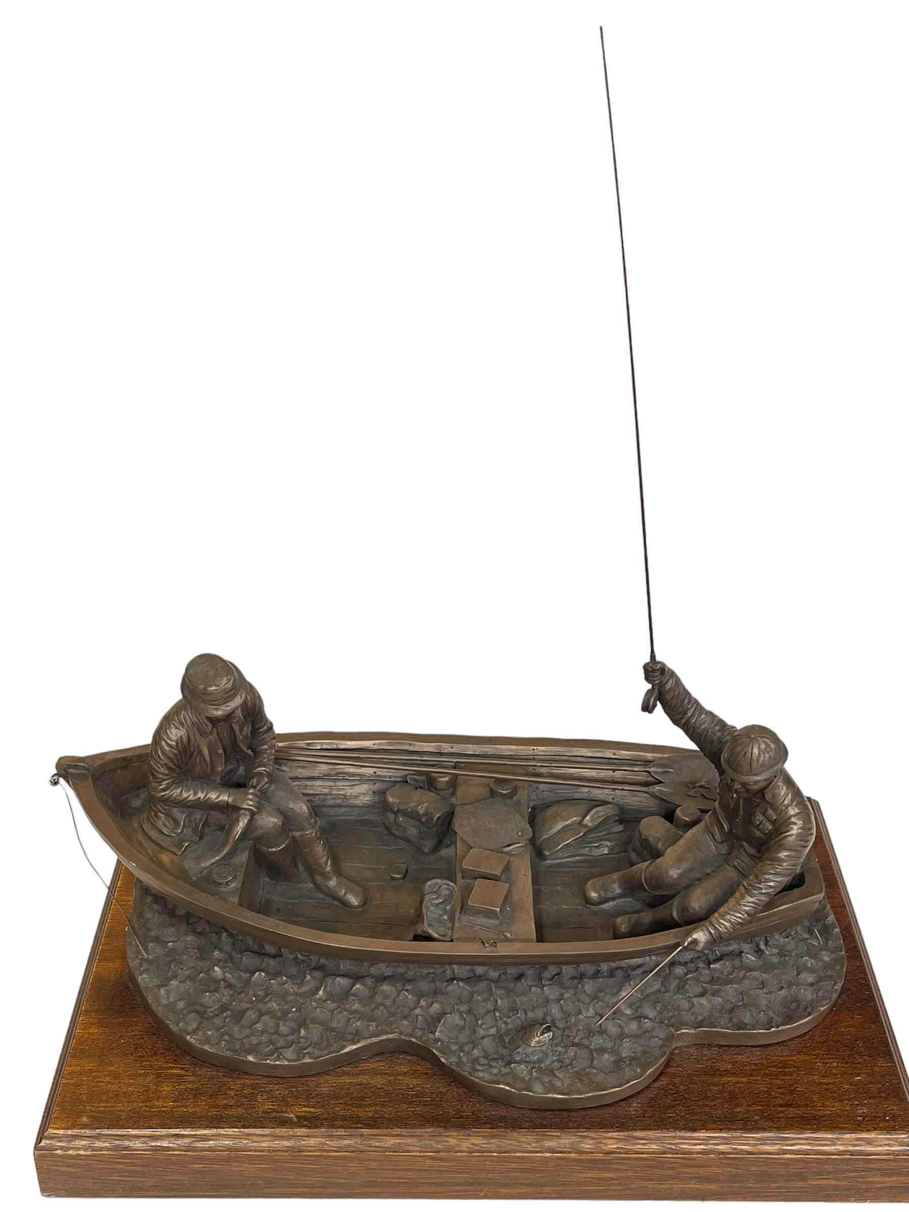 Composite fishermen sculpture on wooden plinth, 45cm long.