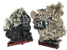 Two large soapstone carvings depicting fish and fauna on wood bases.