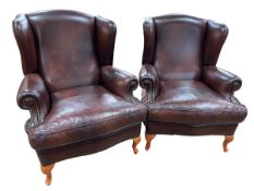 Pair brown and brass studded leather wing armchairs.