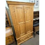 Pine wardrobe having two panelled doors above a base drawer, 193cm by 110cm by 56cm.