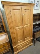 Pine wardrobe having two panelled doors above a base drawer, 193cm by 110cm by 56cm.