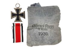 A German WWII Iron Cross with ribbon in original paper bag.