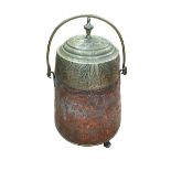 Copper and brass lidded pot with embossed decoration on three feet with swing handle.