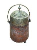 Copper and brass lidded pot with embossed decoration on three feet with swing handle.