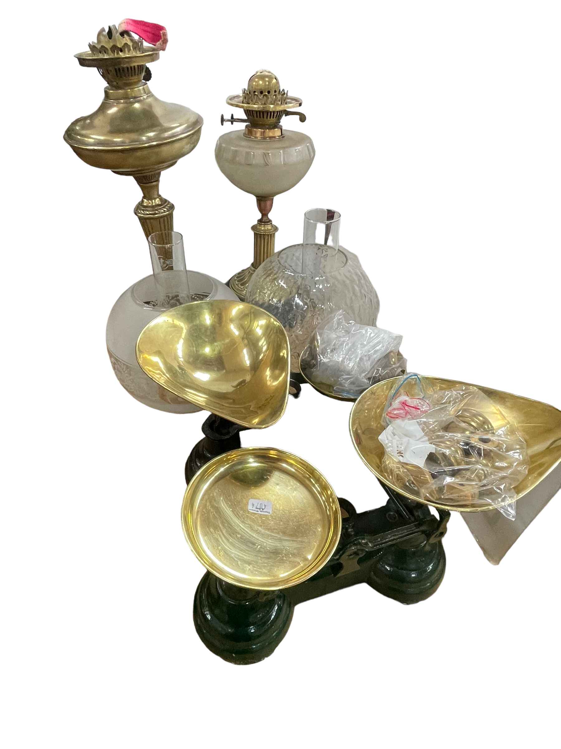 Two brass oil lamps with frosted and clear glass shades and two sets of kitchen scales and weights.