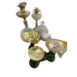 Two brass oil lamps with frosted and clear glass shades and two sets of kitchen scales and weights.