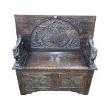 Carved oak Monks bench with carved animal arm terminals, 77cm by 106cm by 50cm (closed).