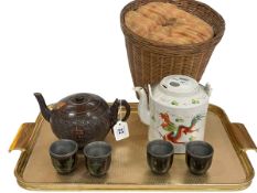 Chinese coconut teapot and four cups and Chinese teapot in wicker basket.