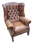 Georgian style tan buttoned leather wing armchair.