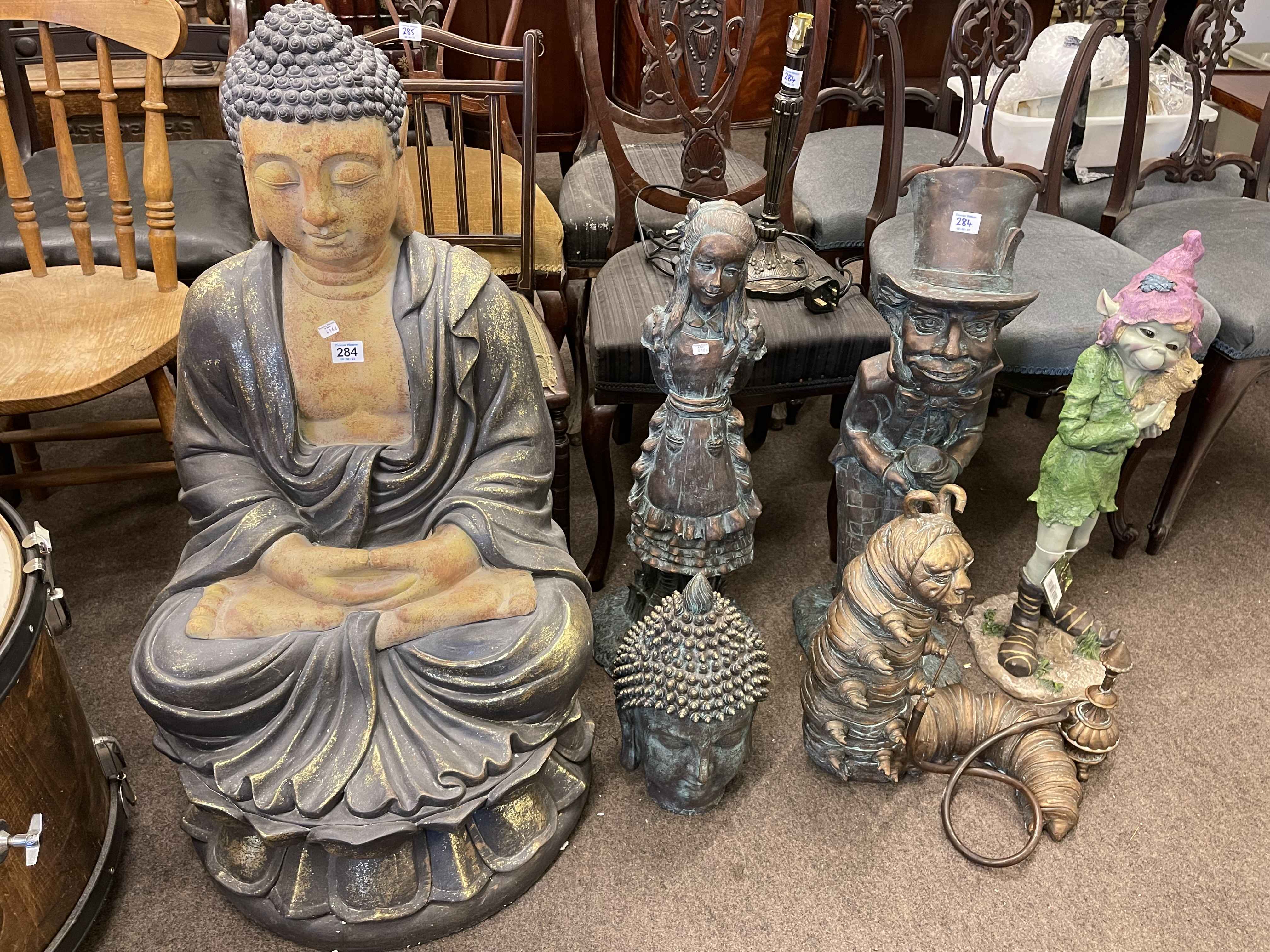 Buddha garden figure, Buddha head, three Alice in Wonderland figures, pixie and table lamp (7).