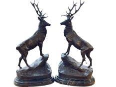 Pair of impressive bronze models of stags on rocky outcrops on marble bases, 74cm high.