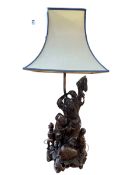 Ornate carved root wood table lamp with shade showing Oriental men, 82cm.