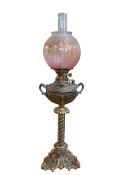 Ornate brass twist columned oil lamp with pink etched shade, 76cm.