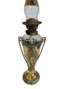 Ornate brass urn style oil lamp with clear glass reservoir.