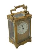 Gilt brass carriage clock with ornate face, 15cm to top of handle.