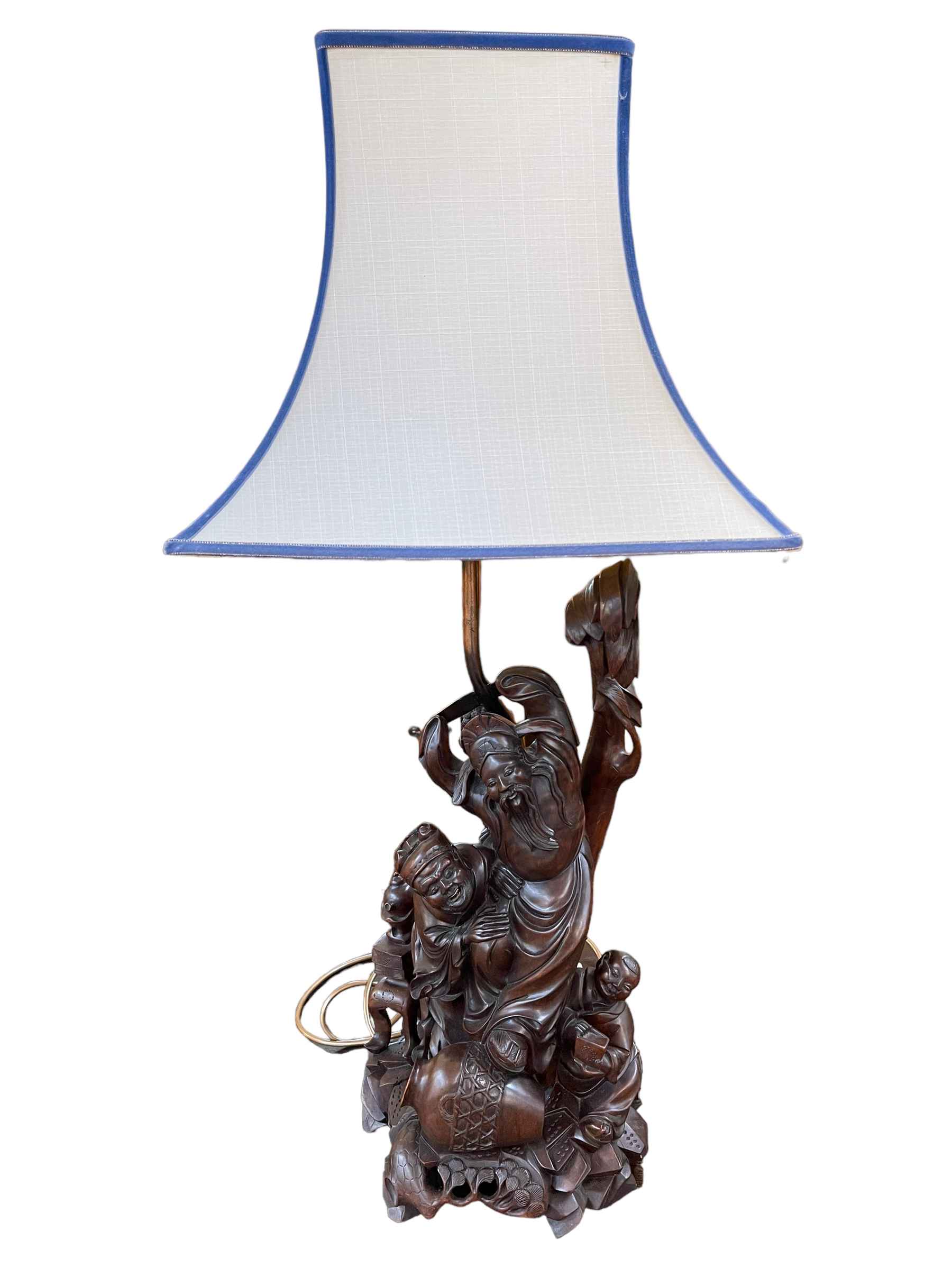 Ornate carved root wood table lamp depicting Oriental men, with shade, 82cm.