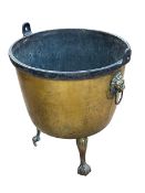19th Century brass log bin raised on three claw feet with lion mask ring handles, 65cm.