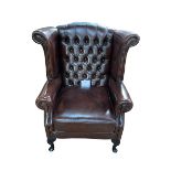 Thomas Lloyd brown buttoned leather and studded wing armchair.